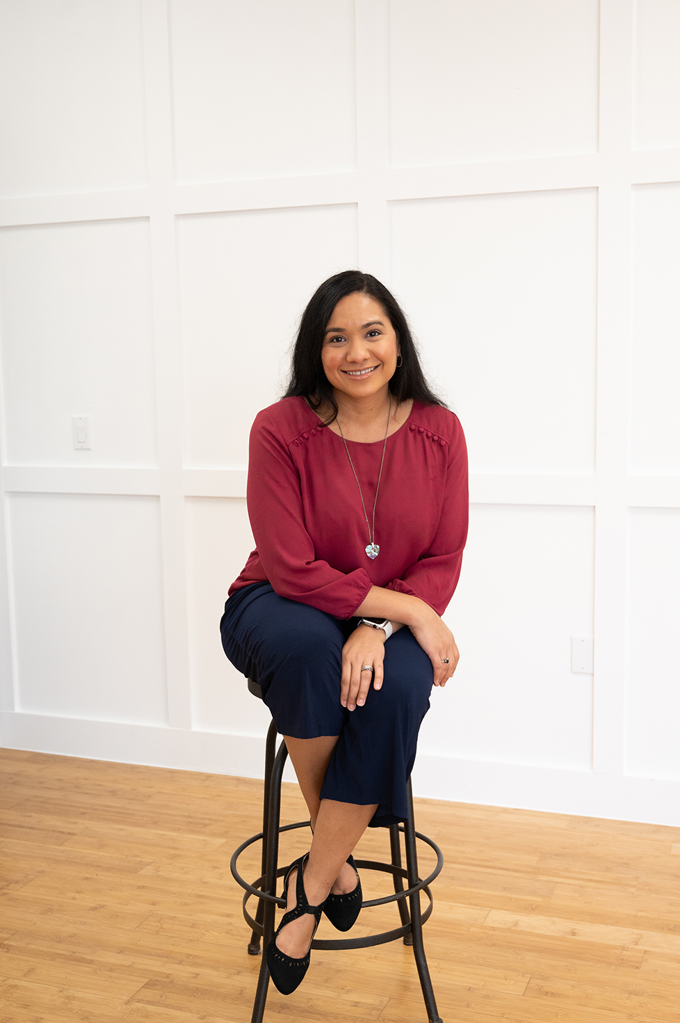 Psychologist Dr. Angelique sitting on a stool with a red shirt